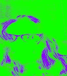 Stylized filtered photograph of the author wearing glasses sitting in front of blinds with a mostly bright green background, with parts of their hair and glasses outlined in purple grape lines. In the left lens of their glasses is a reflection of the author’s cell phone used to take this selfie.