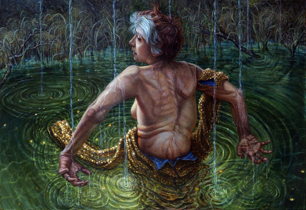 A painted self-portrait of the artist Riva Lehrer. In gloriously rich colors, Riva is depicted wading waist high into a lake, surrounded by reeds, as rain begins to fall around her. The green water swirls and ripples from Riva’s body and the raindrops as they hit the water. She is facing away from us, her upper clothing, golden in color, has been unzipped at the back and hangs from her right arm and is draped around her hips. Her back is the central focus of the image. In fleshy red, pink and orange tones we see how it curves towards the right, protruding outwards at her right shoulder blade. The rain water runs down her back in snaking rivets, over what looks like scar tissue, over muscle, over bone. Riva’s arms are outstretched behind her, seemingly for balance as she glides away from us through the water, her hands weathered and grasping upwards towards the falling raindrops that have pooled there. Her face is turned to the left, and we glimpse her calm expression. The side of her left breasts is also exposed and, like her face, softly lit by a ray of light.