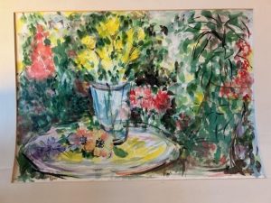 Watercolor of a floral scene. Vase of yellow flowers on oval surface; lavender and apricot-colored flowers lie adjacent to the vase. The brightly lit background includes floral motifs with greenery. The palette features vibrant yellows, reds, and greens.